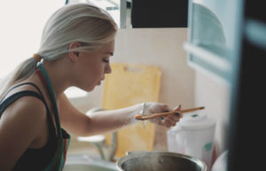 A woman cooking on the stove and increasing air circulation to prevent mold 