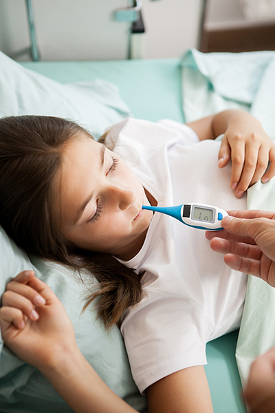 Doctor taking body temperature of her patient in hospital room