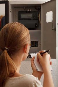 Woman holding a checklist checking her home's electrical system 